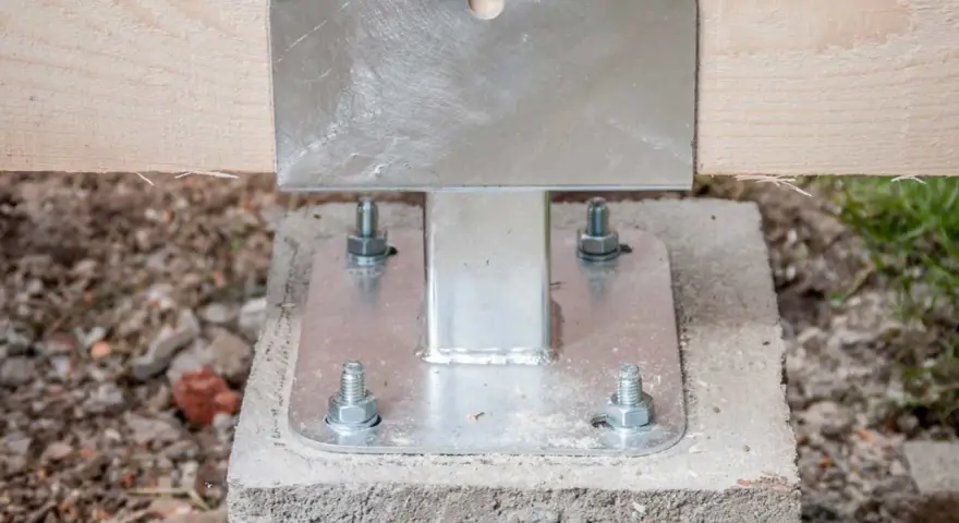 Pied de poteau métallique fixé sur un plot béton à enterrer, soutenant une poutre en bois.