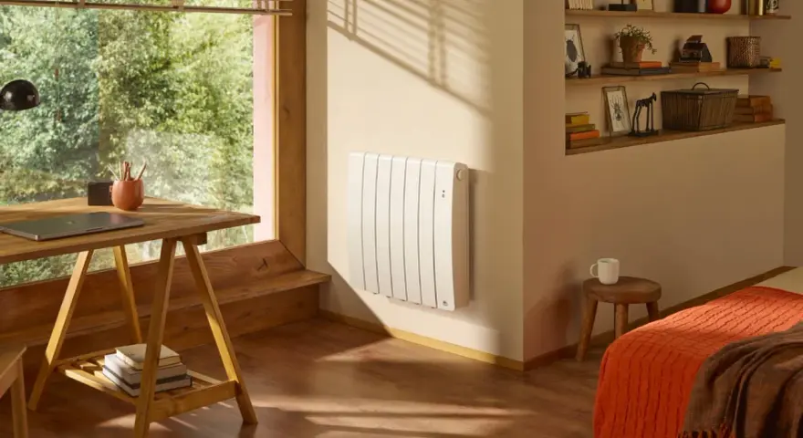 Radiateur blanc mural, discret et efficace, diffusant une chaleur douce grâce à son fluide caloporteur. Un coin bureau et un lit douillet complètent cette pièce chaleureuse.