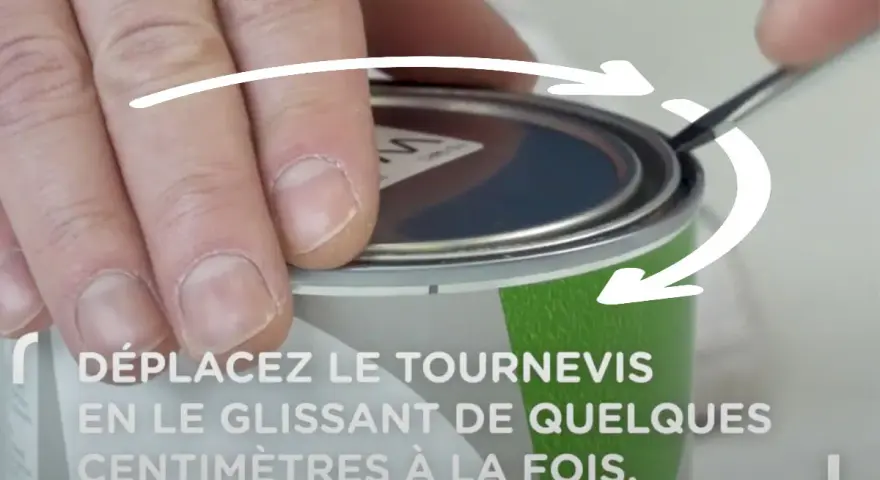 Main tenant un tournevis, on montre comment ouvrir un pot de peinture en faisant levier sur le couvercle.