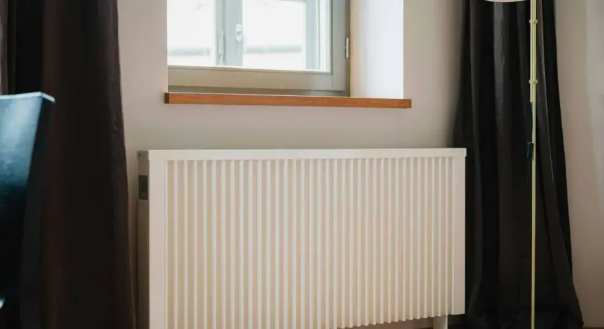 Radiateur électrique blanc moderne près d'une fenêtre. Idéal pour bénéficier de l'aide de l'état pour changer radiateur électrique.