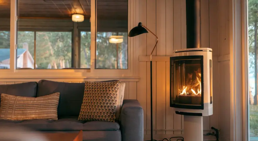 Un poêle à bois moderne, avec un feu vif, est placé à distance du mur en placo, créant une ambiance chaleureuse.