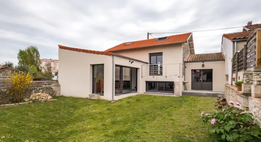 Maison avec extension moderne, jardin verdoyant. Le prix d'une extension maison 20m2 peut varier, mais ce type d'agrandissement offre un espace de vie supplémentaire.