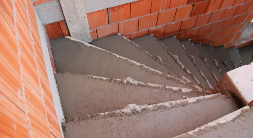 Escalier en béton brut, 5 marches en cours de construction, entouré de briques rouges. Estimation du prix escalier béton extérieur 5 marches.
