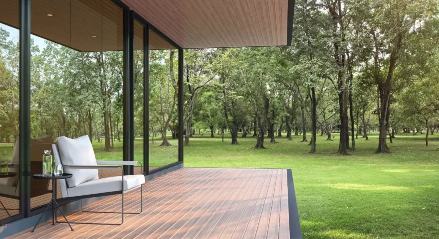 Une terrasse moderne avec un revêtement de terrasse en résine, offrant une vue paisible sur une forêt verdoyante. Un fauteuil confortable invite à la détente.