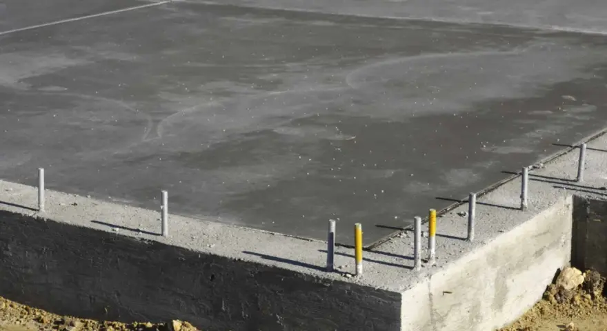 Dalle de béton fraîchement coulée, montrant la base d'une fondation et l'épaisseur de la semelle en béton.