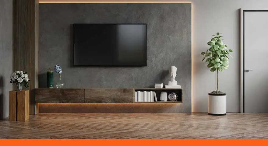 Un salon moderne avec une TV fixée au mur sans voir les fils. Un meuble bas en bois, des livres et une plante verte complètent la décoration.
