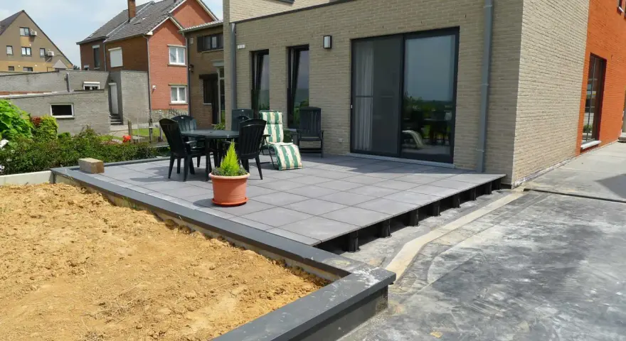 Une terrasse moderne en cours de création, avec des dalles grises surélevées par des plots. Un espace extérieur prêt à être aménagé.