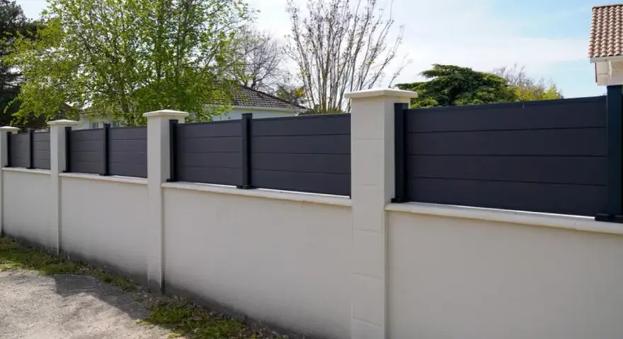 Un mur privatif moderne en composite gris, surmonté de poteaux en pierre, assure l'intimité. Distance à respecter pour une belle clôture.