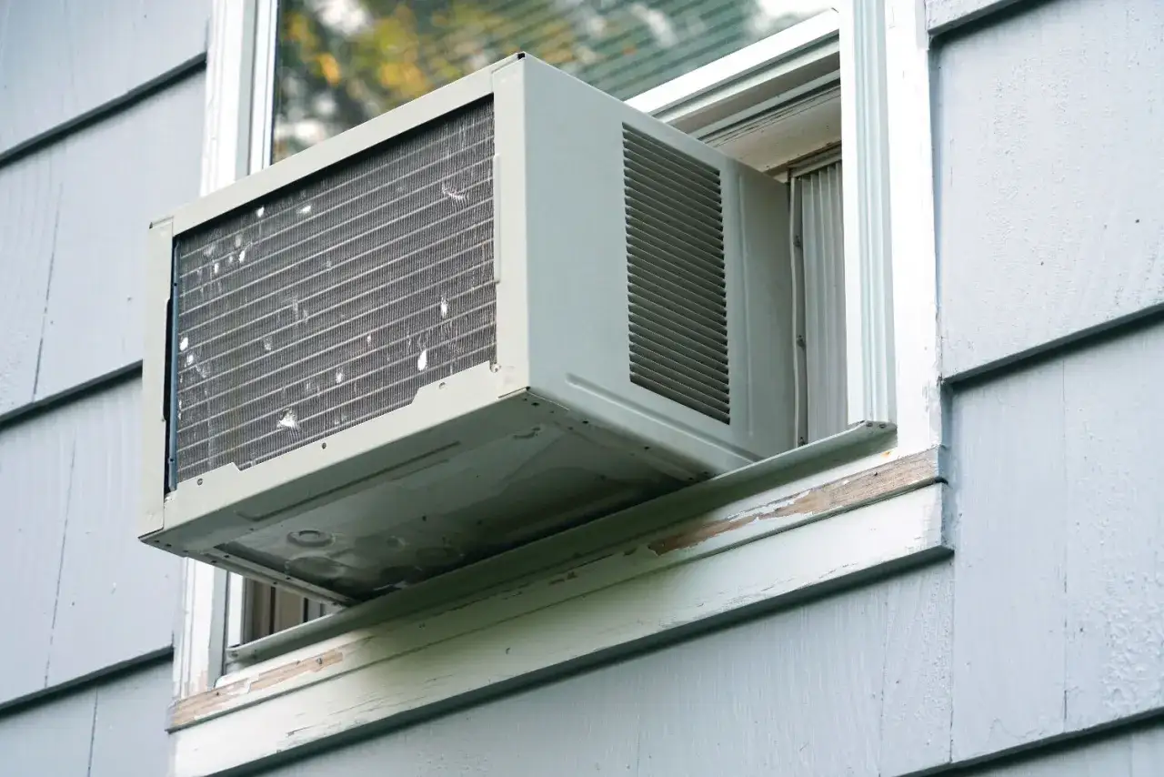 Climatiseur mobile réversible mode chauffage installé dans une fenêtre. L'appareil est prêt à diffuser de la chaleur ou de la fraîcheur.