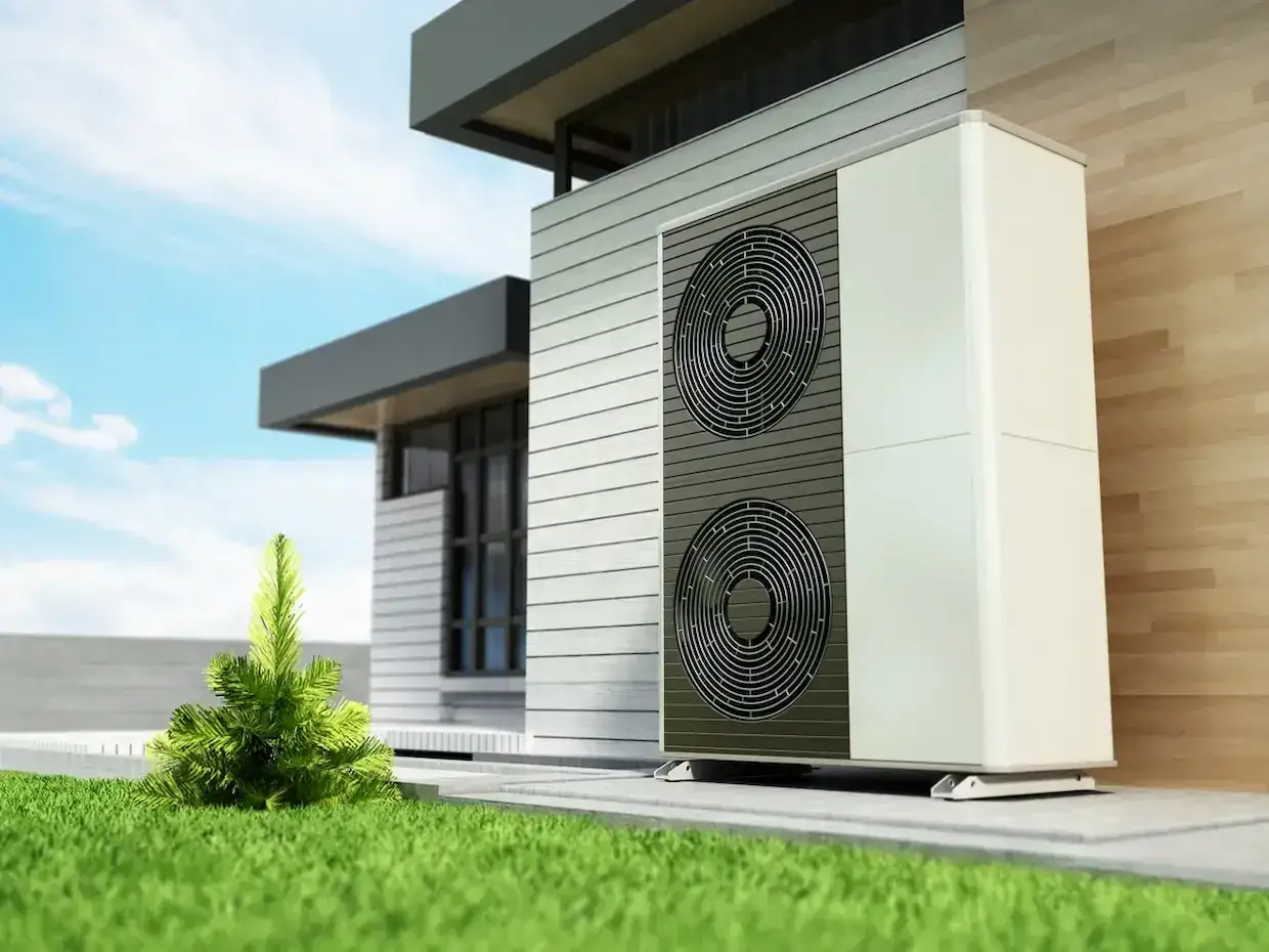 Unité extérieure d'une pompe à chaleur pour un prime renov. Installation moderne sur une pelouse verte devant une maison contemporaine.
