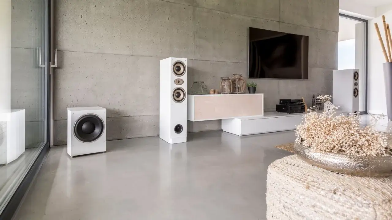 Salon moderne avec mur en enduit sur béton intérieur, système audio blanc, TV et mobilier épuré.
