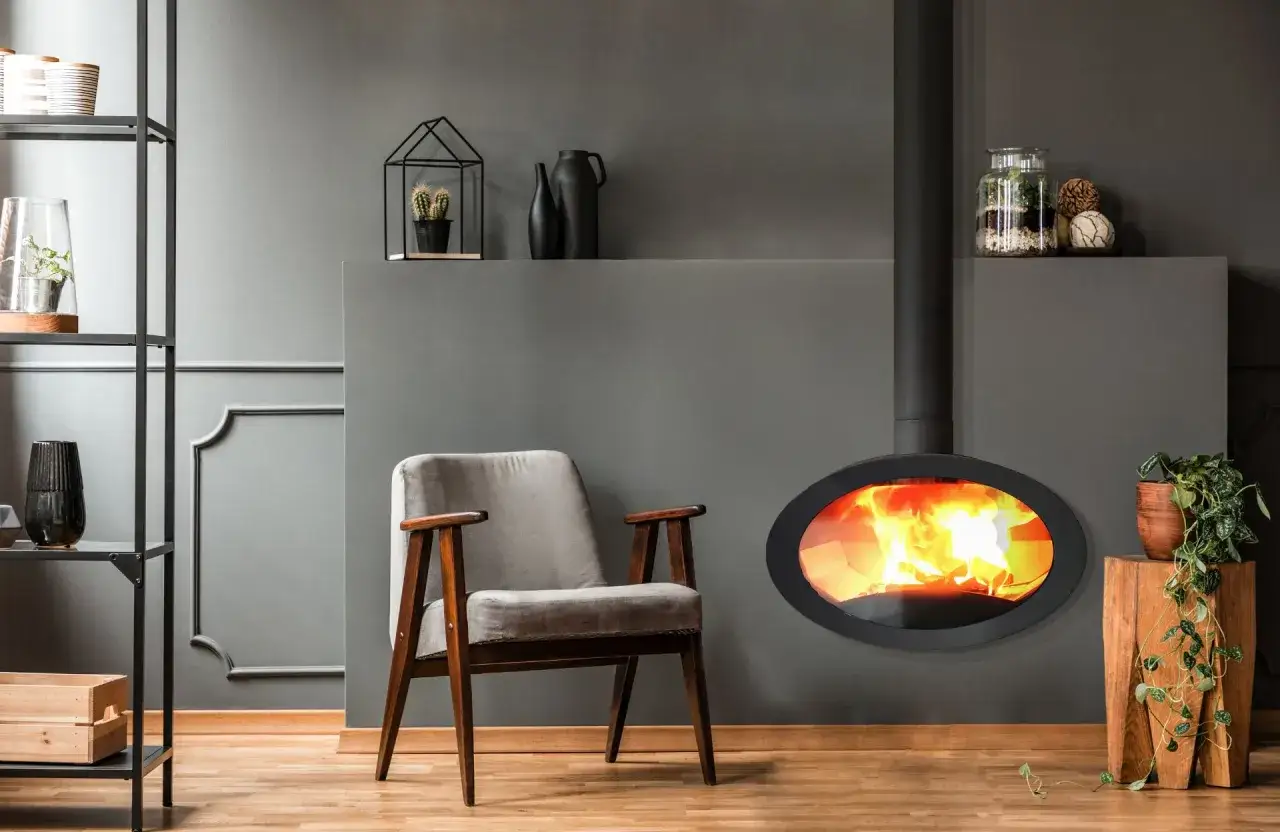 Un fauteuil confortable invite à la détente près d'un poêle à bois ou granulés aux flammes vives.