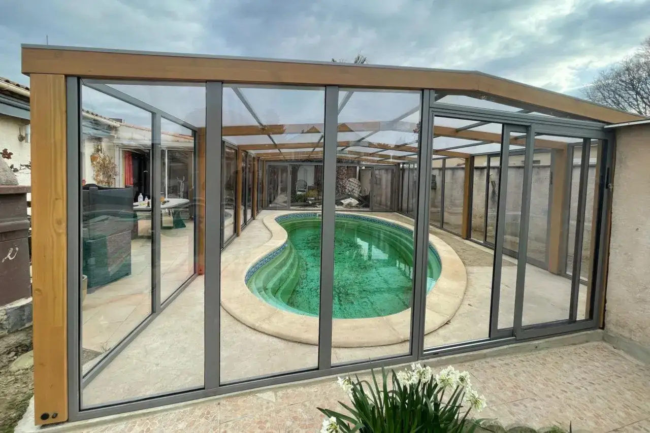Abri de piscine hors sol moderne en verre et bois, offrant une vue sur la piscine. Idéal pour apprendre comment fabriquer un abri piscine hors sol.