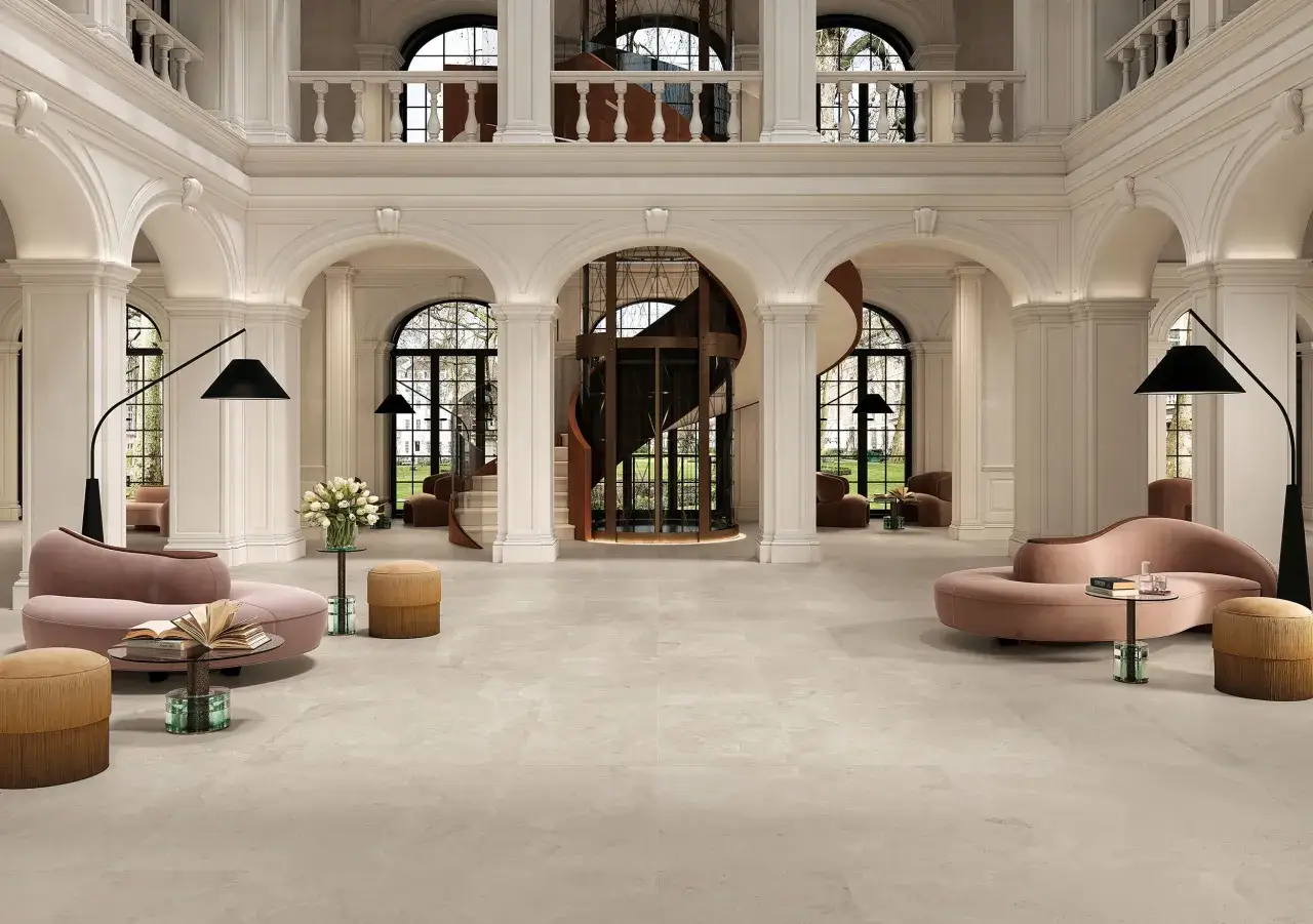 Un grand hall d'entrée avec un carrelage pièce de vie tendance, des canapés roses, un ascenseur vitré et un escalier en colimaçon.
