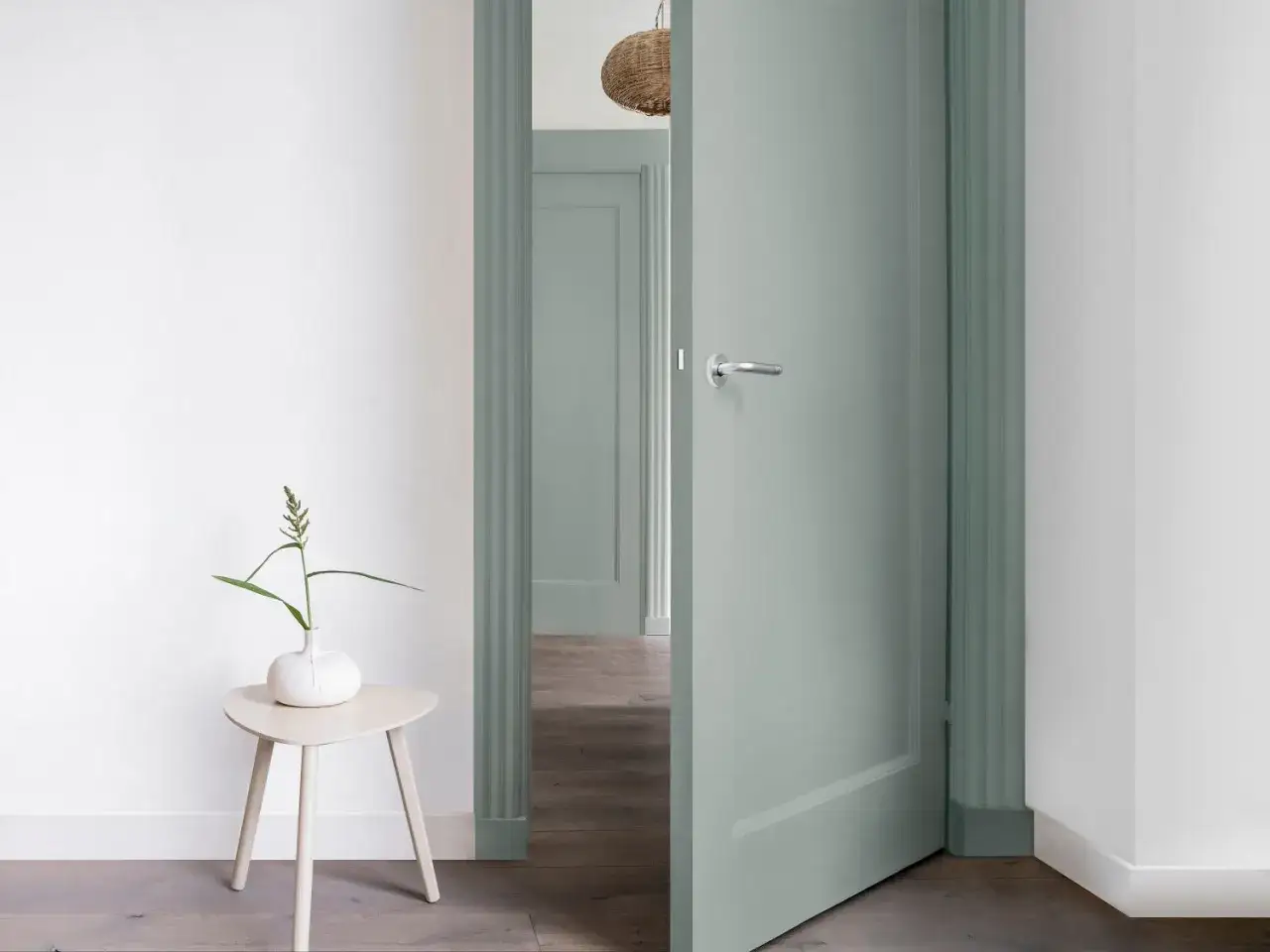 Peinture douce pour un couloir et des portes, créant une ambiance apaisante. Une plante verte sur une table basse ajoute une touche de nature.