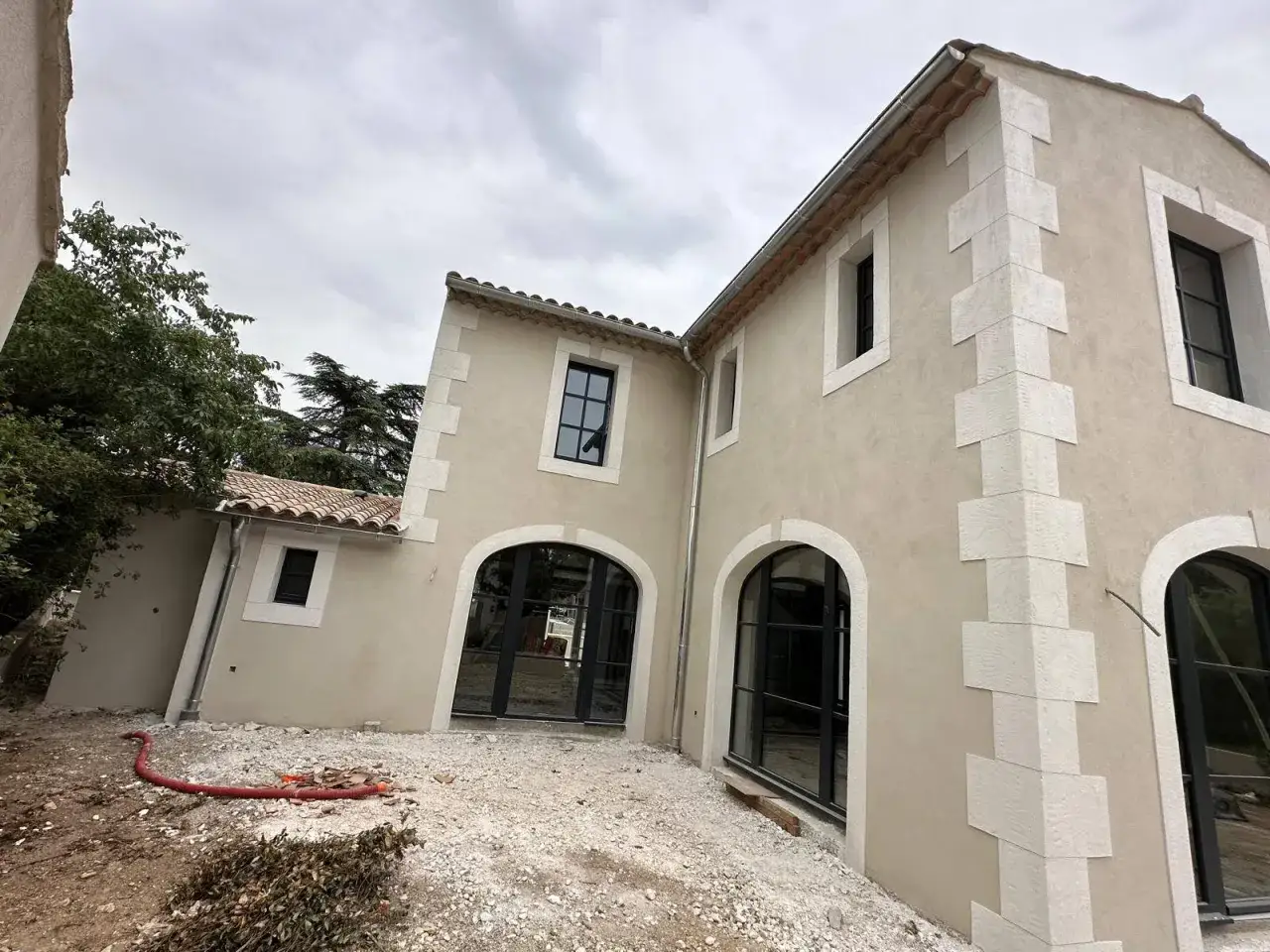 Maison en cours de rénovation. On refait un enduit extérieur sur un enduit existant, avec des encadrements de fenêtres en pierre.