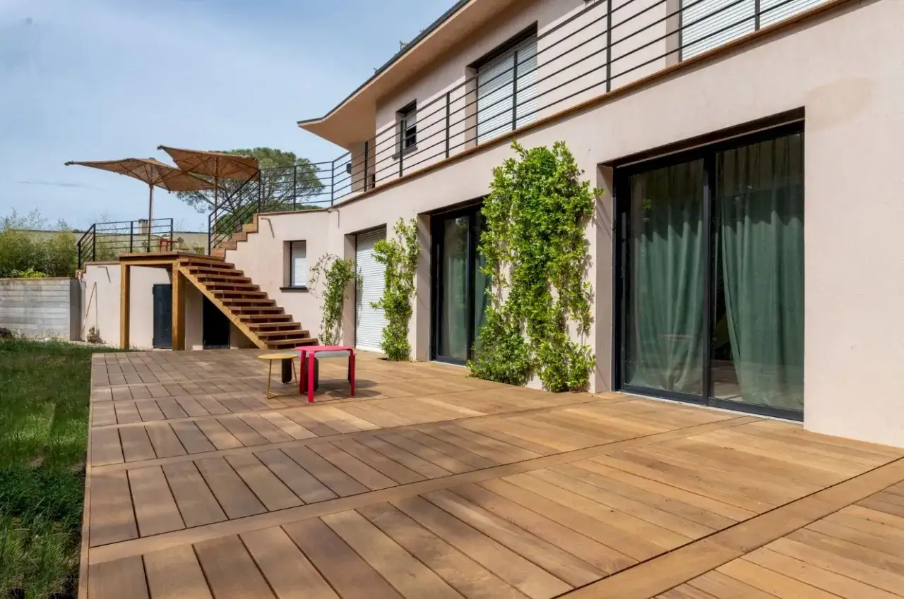 Une nouvelle terrasse en bois a été refaite sur une ancienne, avec un escalier menant à un étage supérieur.