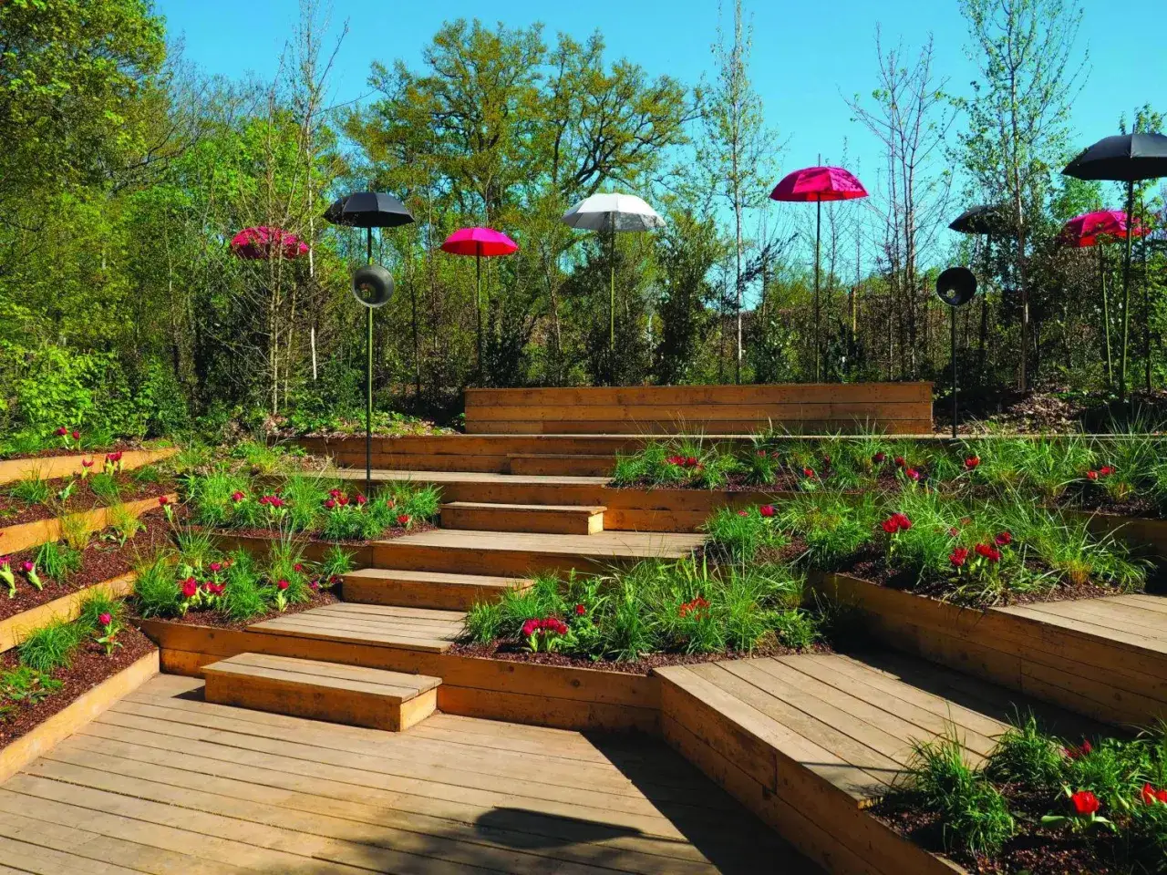 Un jardin aménagé avec des terrasses en bois et des parterres de fleurs. La profondeur marche escalier extérieur crée un chemin sinueux à travers la végétation luxuriante.