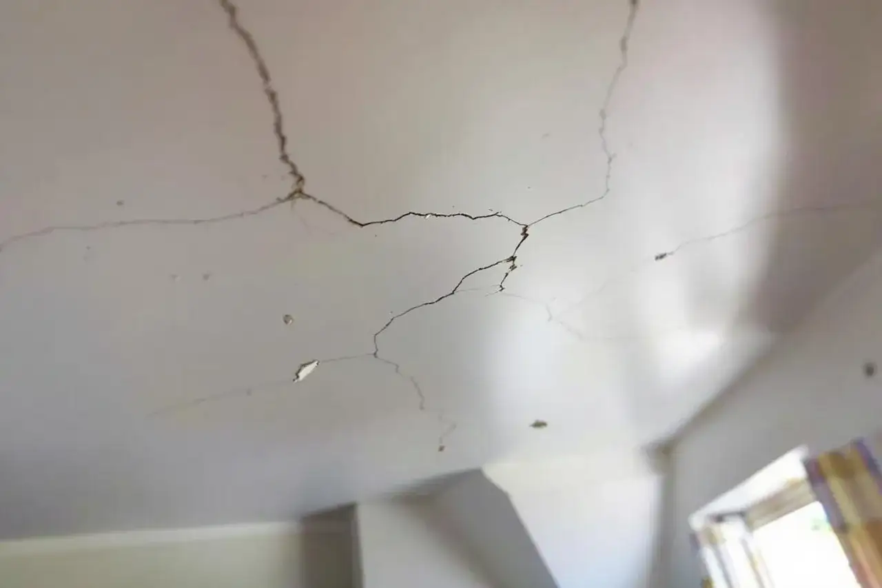 Le plafond qui s'effrite montre des fissures sombres et inquiétantes, signe d'un problème structurel.