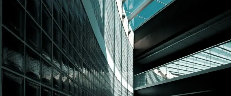 Mur extérieur en pose brique de verre, reflétant la lumière et créant des jeux d'ombres sur la façade moderne.
